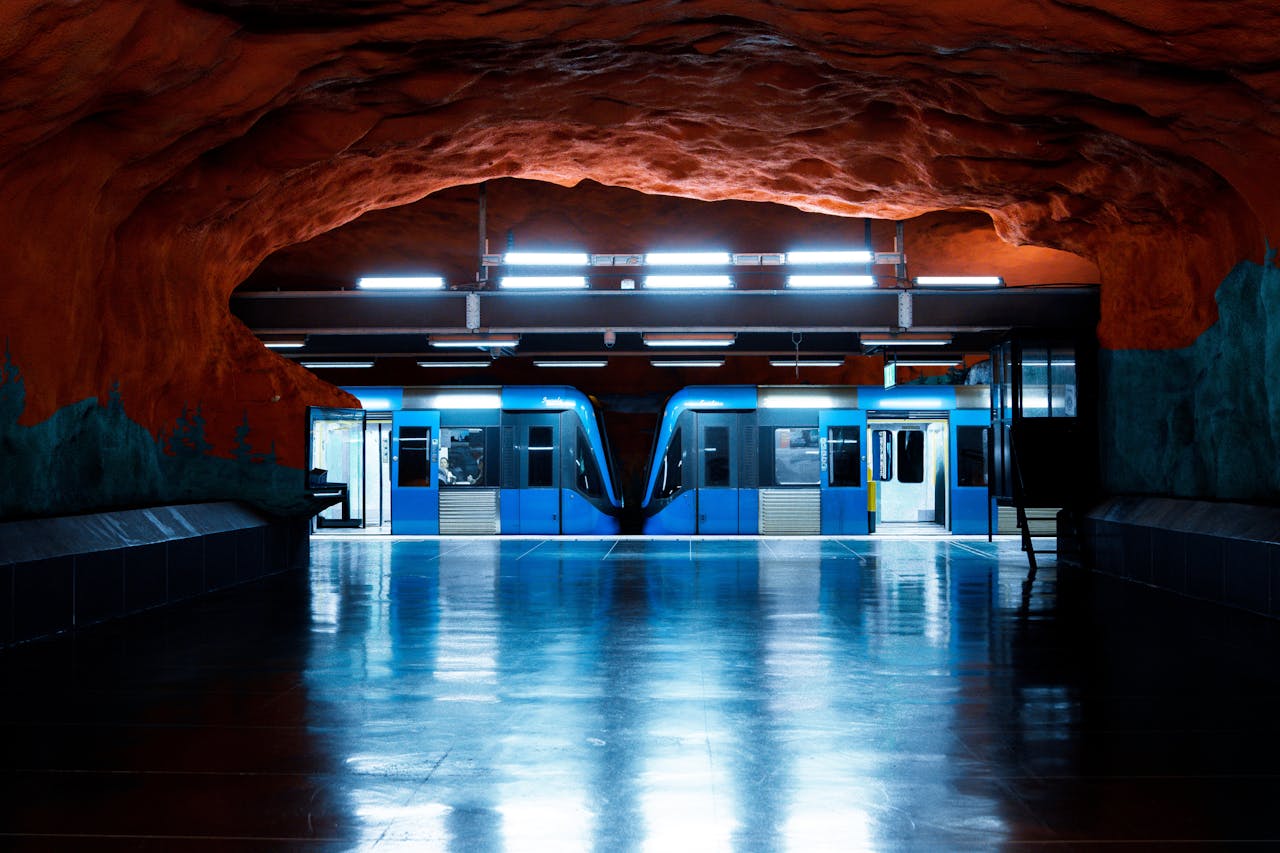 home-hero-bg Elegant view of Stockholm metro station with distinctive cave-like walls and bright blue train.